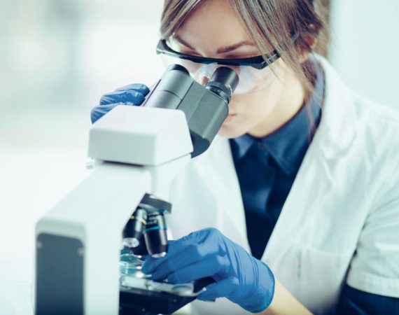 Cell therapy scientist looking through a microscope