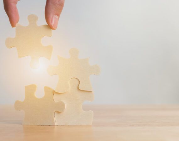 Hand of male or female putting jigsaw puzzle connecting on woodden desk, Strategic management and business solutions for success